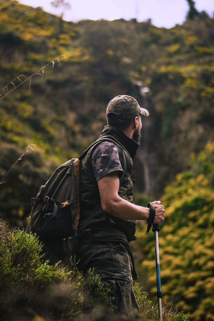 Man with hiking gear explores lush forest landscape, embodying adventure and nature.