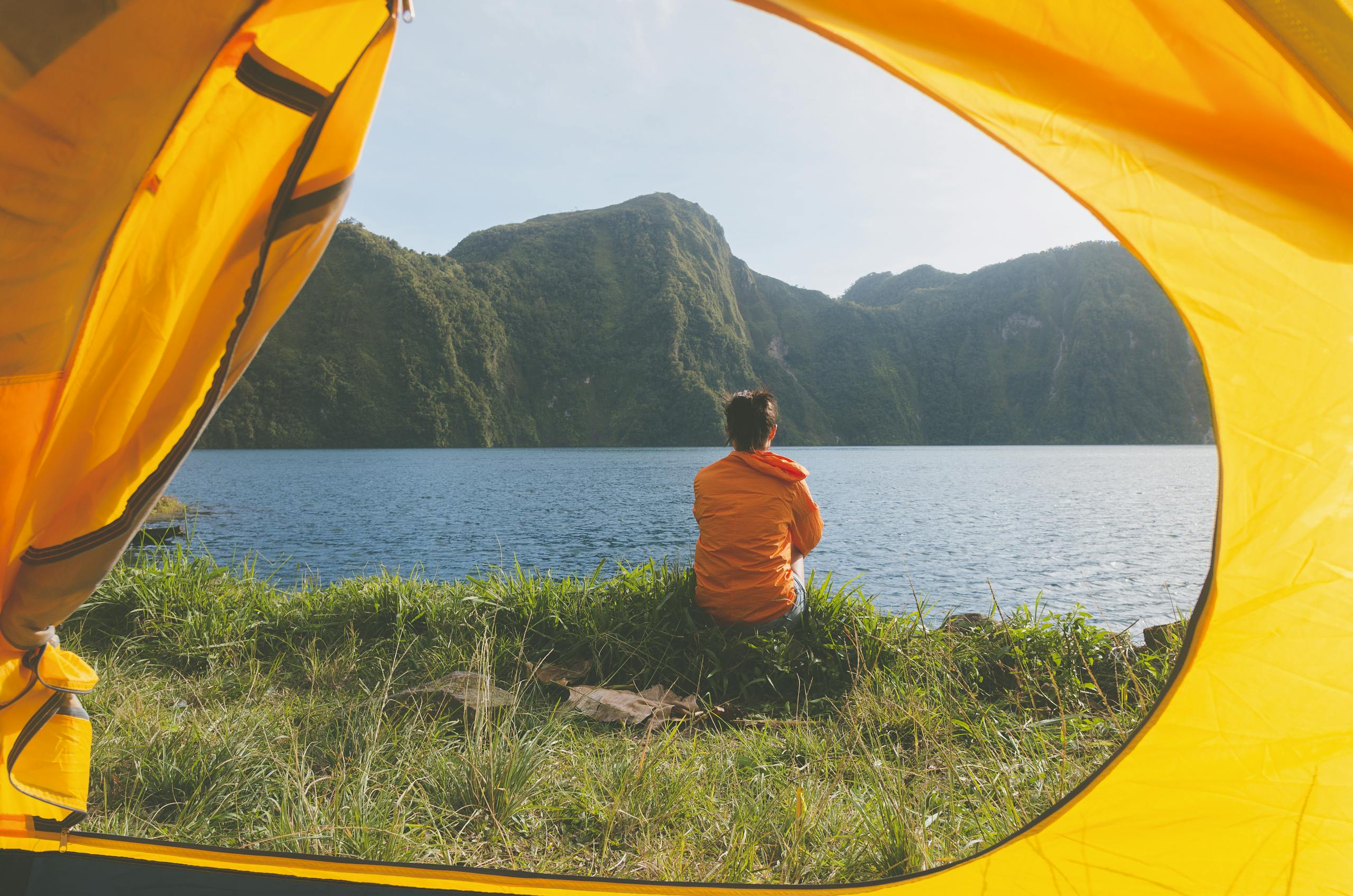 Serene view of a woman in a yellow tent, overlooking a picturesque lake and mountains in T'boli, Philippines.